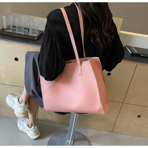 Close-up of pink leather tote bag with fine litchi grain and gold logo detail