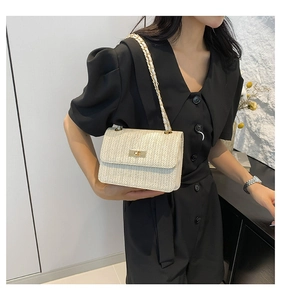 Detail of straw woven texture with gold chain strap on a cream crossbody bag