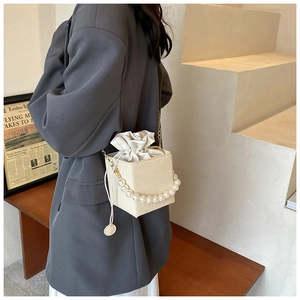 Detail of square straw bucket bag with pearl handle and drawstring closure