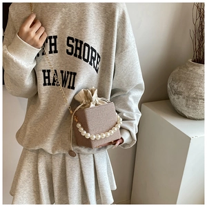Detail of woven square bucket bag with pearl handle and drawstring closure for women