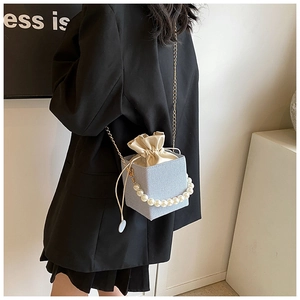 Detail of light blue denim bucket bag with pearl handle and golden chain strap for women