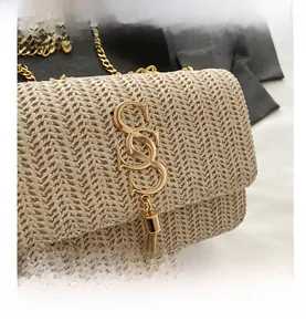 Detailed macro view of woven straw bag featuring gold SS buckle and chain tassel