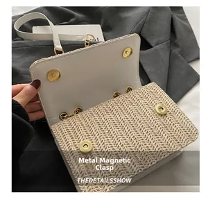 Detail of woven straw bag showing gold magnetic clasps and beige texture with white leather