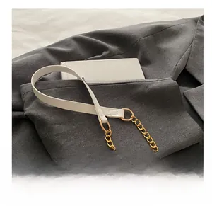 Detail of white faux leather and gold chain shoulder strap on a straw crossbody bag