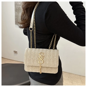 Detail of a beige woven chain bag with gold SS logo and metal tassel on a model