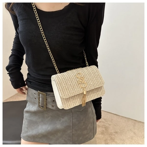Detail of woven straw handbag with gold double S hardware and chain strap