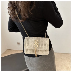 Detail view of woven straw chain bag with gold SS logo and tassel on model back