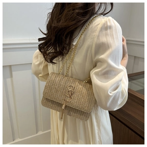 Detail of straw woven bag with gold chain and metal tassel on a crossbody model