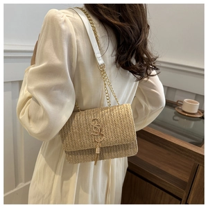 Detail of a straw woven chain crossbody bag with golden S logo and summer vacation vibes