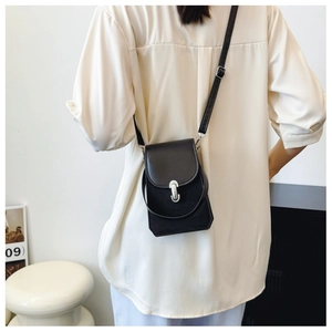 Detail of black crossbody phone bag showing silver U-shaped buckle and dual strap design