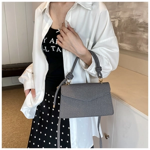 Detail of dark grey woven textured handbag featuring a knotted handle and golden ring hardware