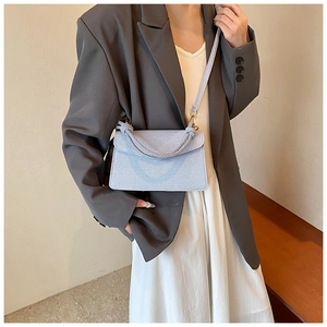 Detail of light blue textured square bag with thick braided handle and thin shoulder strap