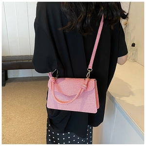Detail of pink striped fabric crossbody bag featuring a unique decorative knot handle