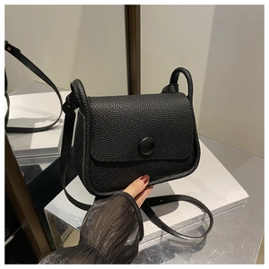 Detail view of the black lychee pattern leather saddle bag with round magnetic clasp