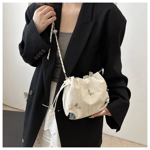 Detail of white marble texture drawstring bag with silver butterfly metal charms