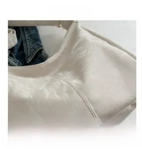 Detail of white wrinkled leather tote bag showing high-quality stitching and glossy texture