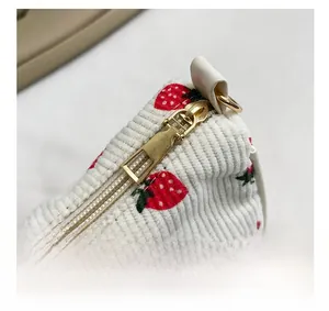 Makroaufnahme des goldenen Reißverschlusses an der weißen Cordtasche mit Erdbeermuster