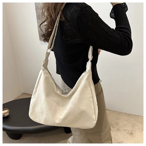 Detail of off-white hobo bag showing wrinkled texture and adjustable shoulder strap