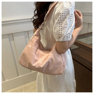 Close-up of pink hobo shoulder bag with pleated texture worn on model's shoulder