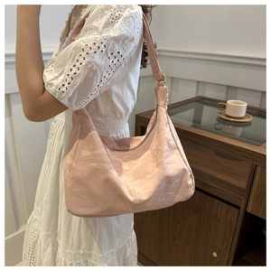 Close-up of pearl pink pleated tote bag on a wooden table with home decor