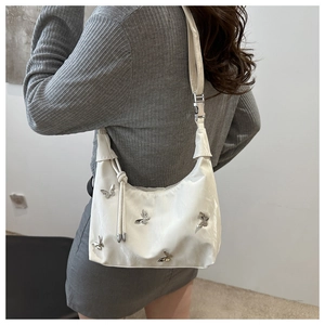 Detailed side view of white crescent bag with silver butterfly studs on a model