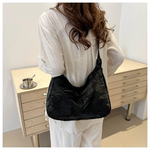 Detail of a large black tote bag with unique pleated texture worn over the shoulder
