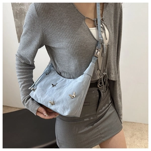 Detail of light blue hobo bag with silver butterfly charm and pleated texture