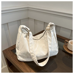 Close-up of beige tote bag with pleated texture, gold buckle, and top zipper closure