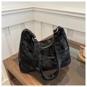 Detail of black crescent tote bag featuring pleated texture and silver zipper closure