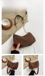 Detailansicht der braunen Cord-Schultertasche mit Erdbeermuster und goldener Kettenriemen