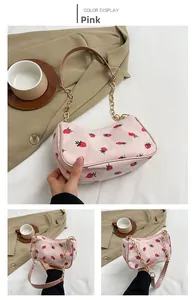 Detail der rosa Cord-Schultertasche mit Erdbeerdruck und goldener Kettenschultergurt