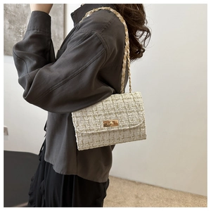 Detail of tweed crossbody bag featuring gold metal turn-lock and elegant chain strap