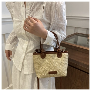 Detail of hand-woven bucket bag with cream straw body and brown leather trim detailing