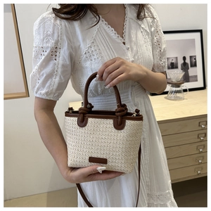 Close-up of woven straw texture and premium brown leather handles on a summer bucket bag