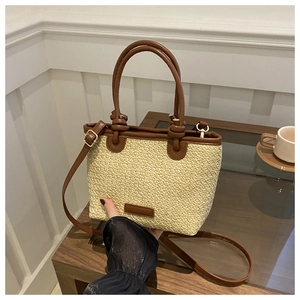 Close-up of straw woven texture with dark brown leather handles and adjustable strap