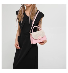 On-body view of a pink crossbody bag featuring a beige woven flap and gold metal buckle