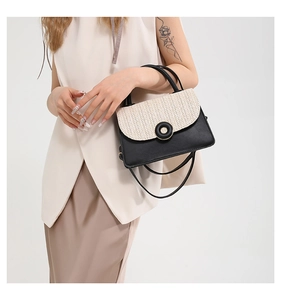 Detail of woven straw and black leather crossbody bag with round metallic clasp