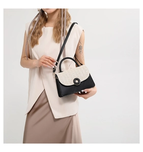 Detail of woven straw texture and black leather contrast on elegant crossbody handbag