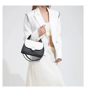 Gros plan sur le sac à main en cuir bicolore noir et blanc avec boucle ronde en métal