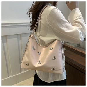Detail of light pink leather tote bag with silver butterfly studs and chain strap