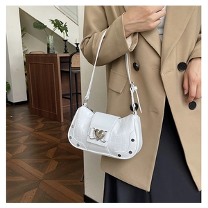 Detail view of white crocodile pattern shoulder bag with heart buckle and metal rivets
