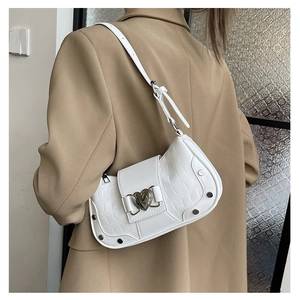 Detail of white crocodile pattern shoulder bag with silver heart buckle and metal rivets