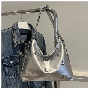 Close-up of metallic silver tote with 3D butterfly studs and metal chain strap