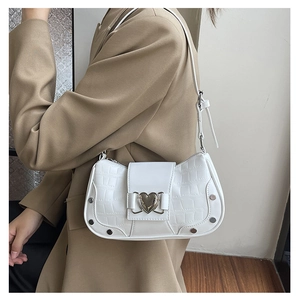 Close-up of white croc-embossed shoulder bag featuring heart buckle and silver rivets