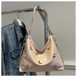 Detail of silver 3D butterfly charms on a cream PU leather hobo shoulder bag