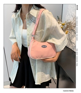 Detail of pink nylon shoulder bag featuring white contrast trim and oval brand logo