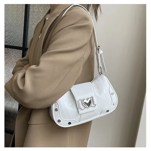 Detail of white crocodile pattern underarm bag with silver heart buckle and metal rivets
