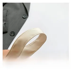 Detailed close-up of smooth cream satin shoulder strap with refined stitching