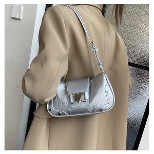 Detail of silver crocodile-patterned underarm bag with golden heart buckle and studs