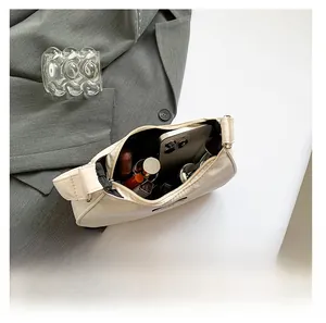 Spacious interior of beige nylon crescent bag holding phone and cosmetics